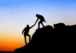 Silhouette of helping hand between two climber
