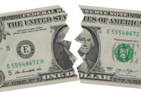 Close up of US One Dollar bill torn in half isolated on white background.
